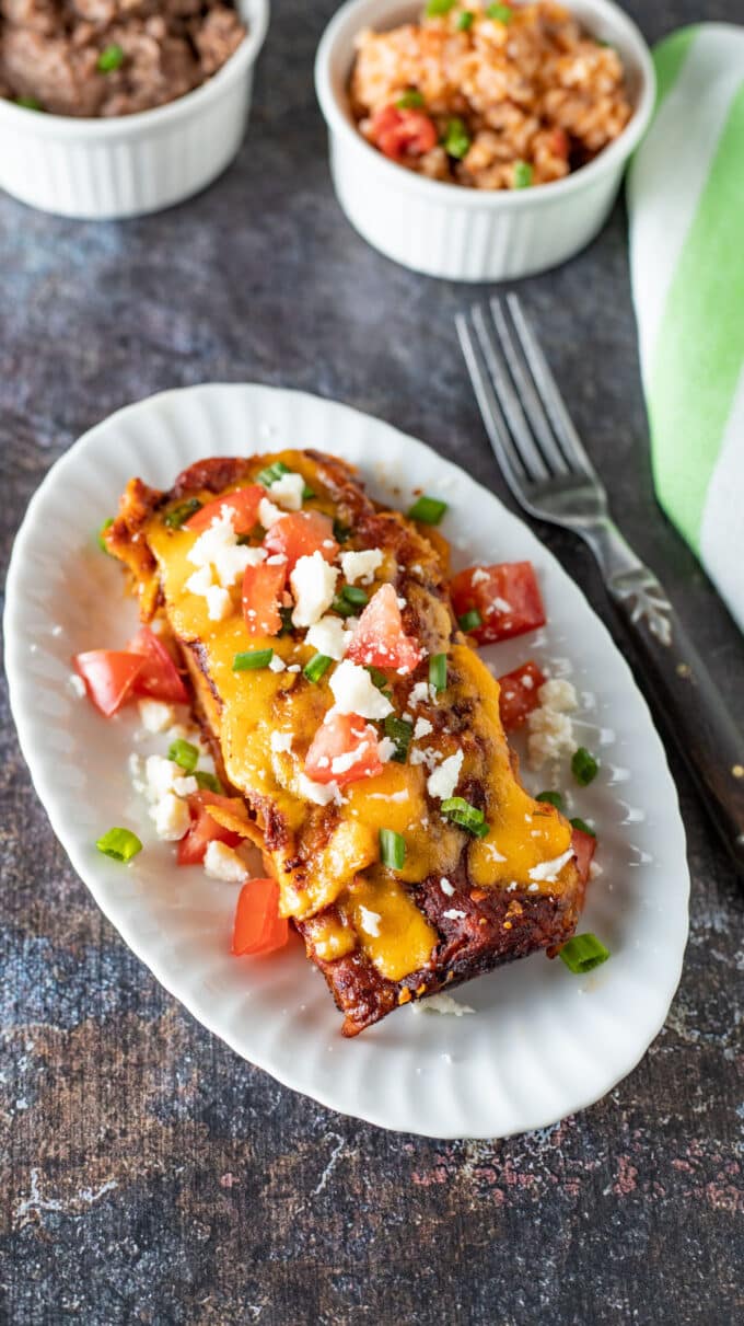 Enchiladas with melted cheese and colorful toppings.