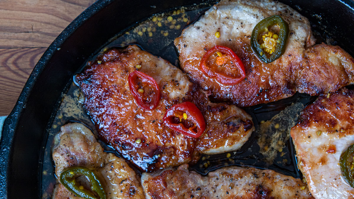 Pork chops smothered in sweet and spicy jalapeno sauce Spicy chops in cast iron pan.
