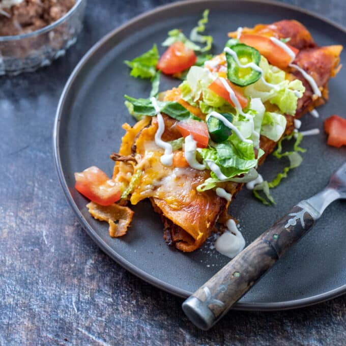 2 enchiladas on grey plate.