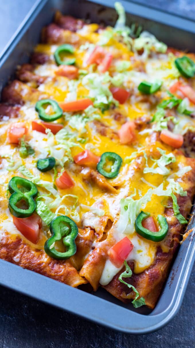 Metal pan filled with cheesy enchiladas.
