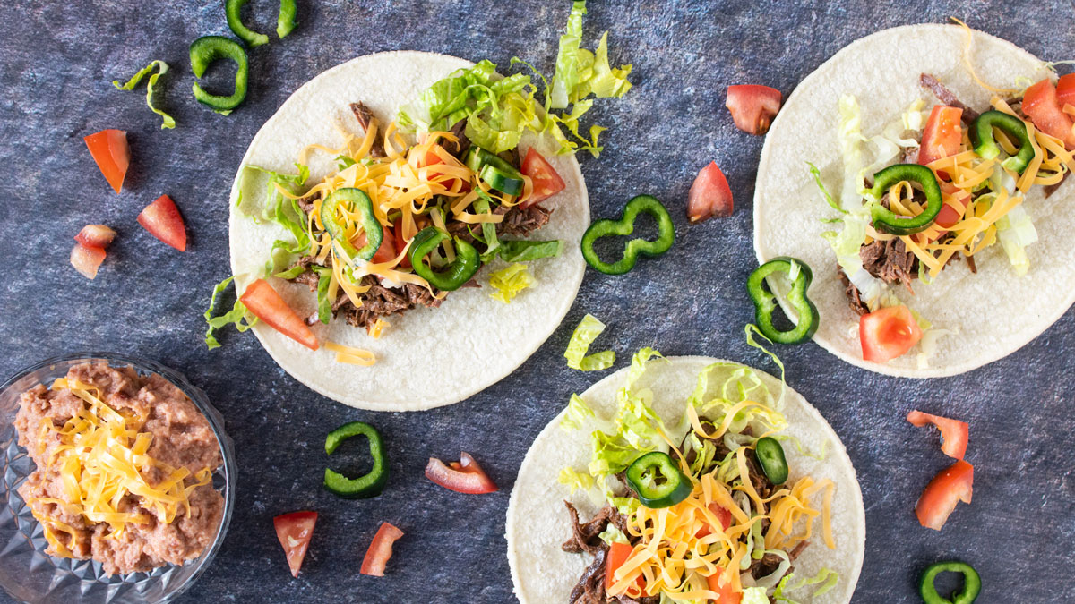 Overhead photo of 3 venison tacos with toppings.