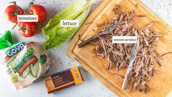 Ingredients for tacos; pulled venison, lettuce, tomatoes, cheese, tortillas..