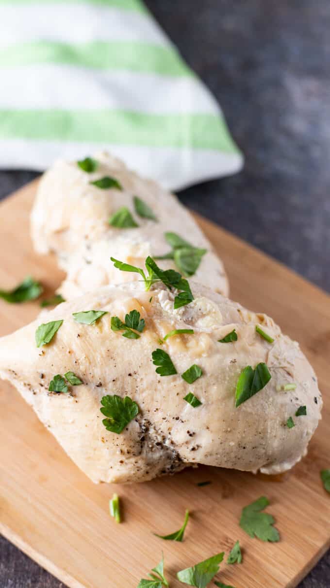 Two chicken breasts on wooden board.