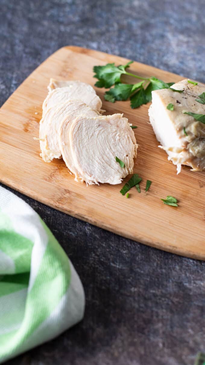 Sliced chicken breast on wooden board.