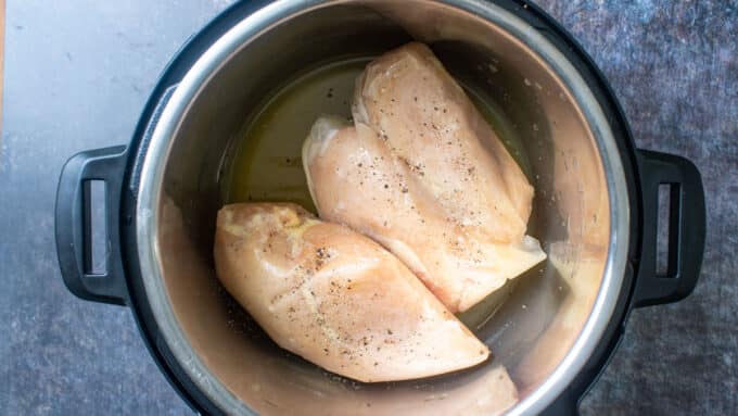 Frozen chicken pot seasoned with salt and pepper and chicken stock in instant pot.