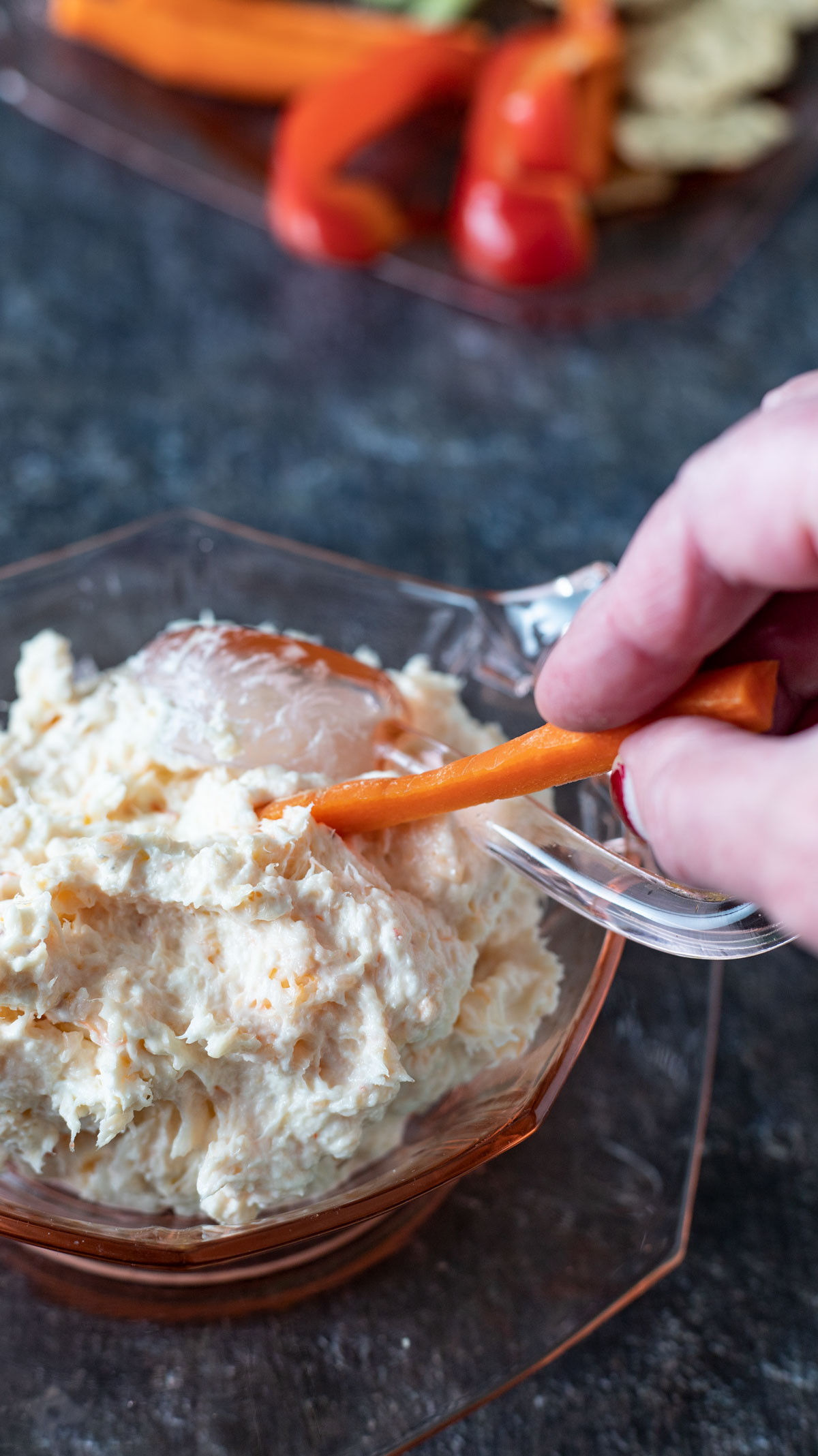 Hand scooping carrot stick into dip.
