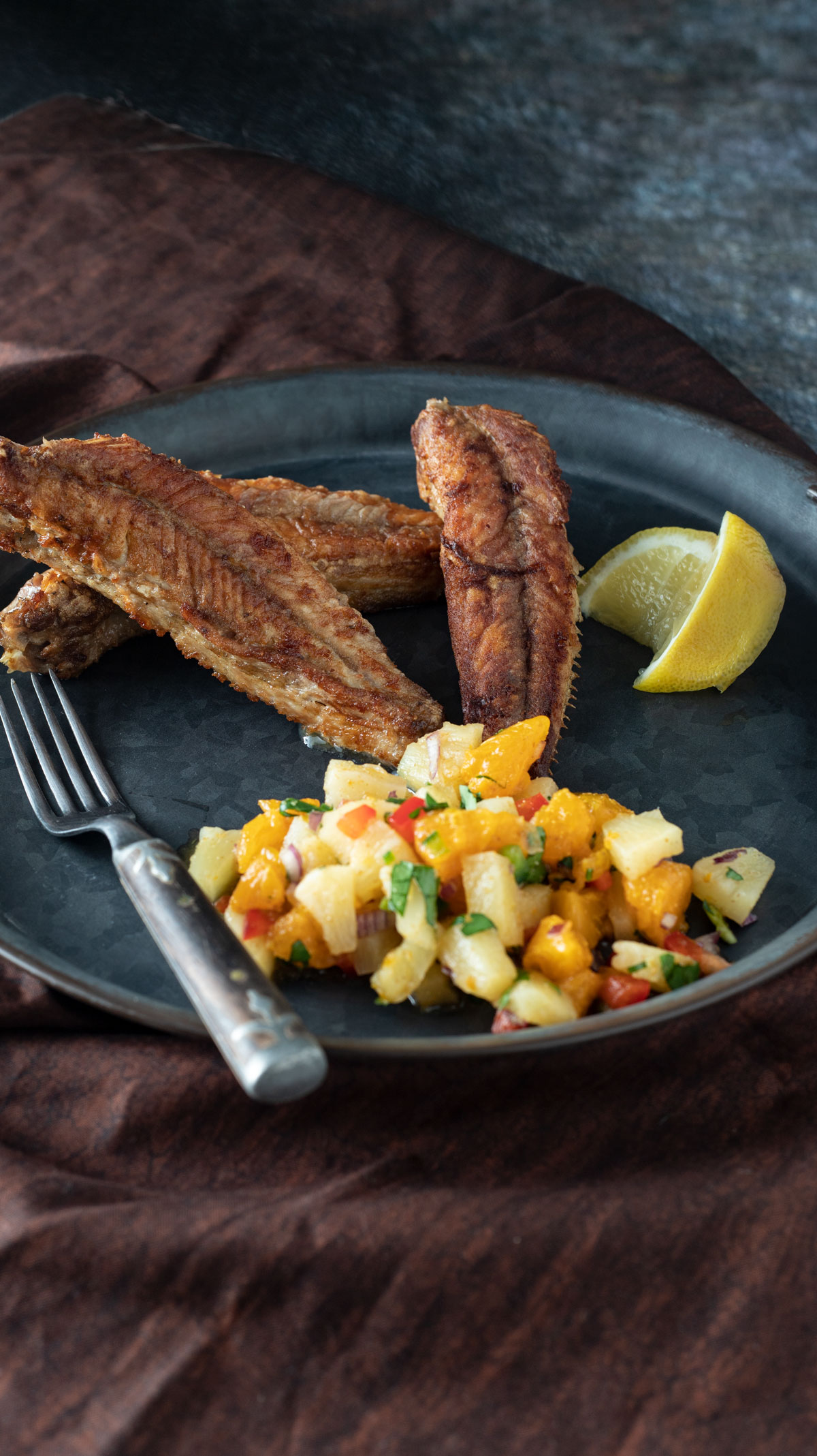 Fish fry with salsa and lemon wedges.