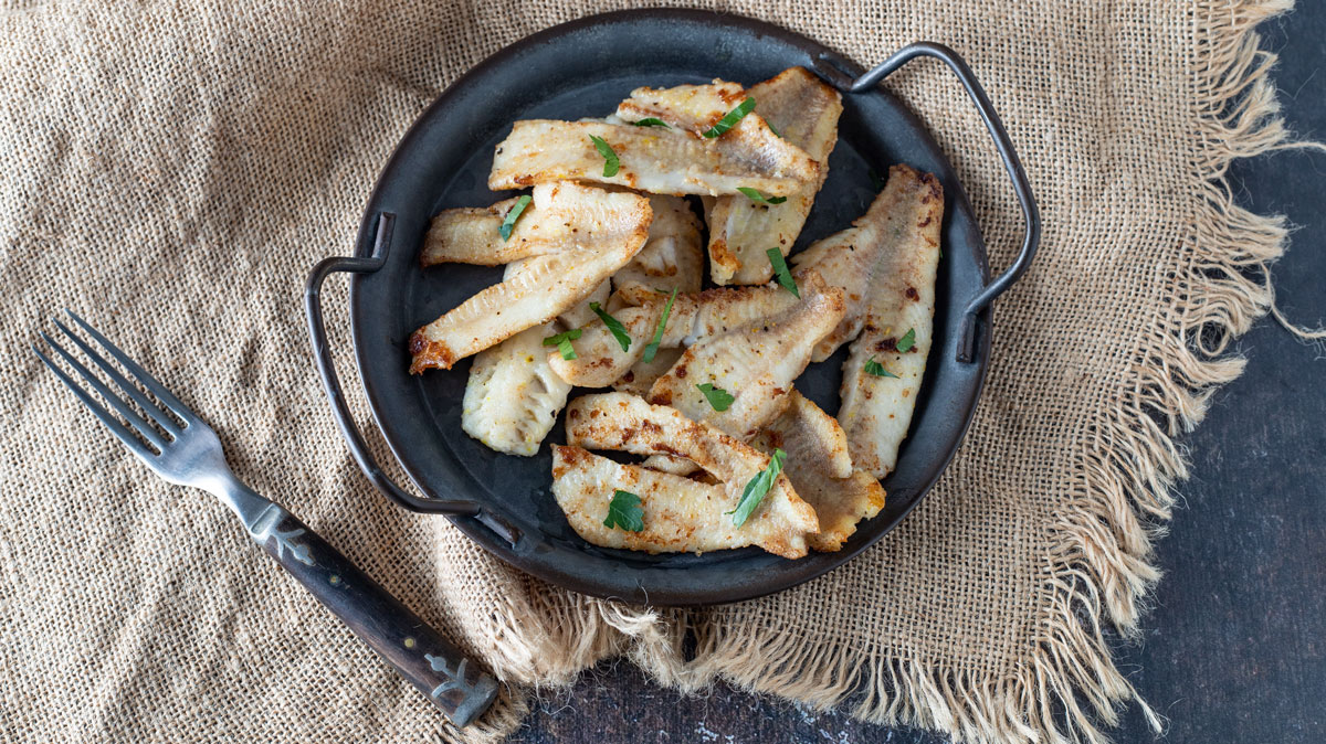 Tray of fried perch on a burlap background.