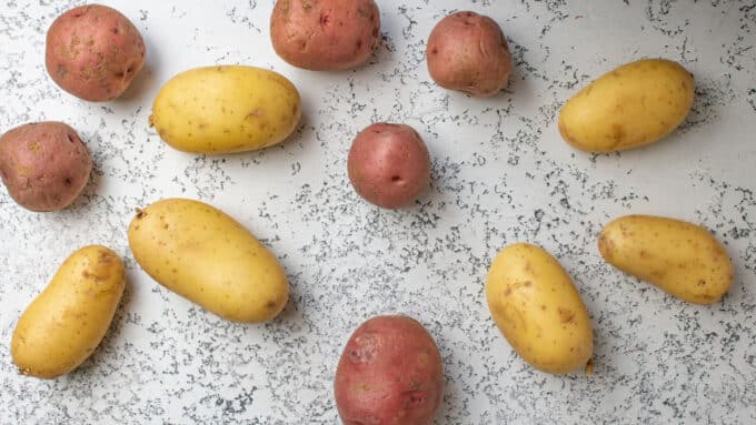 Red and yellow potatoes on distressed white board.