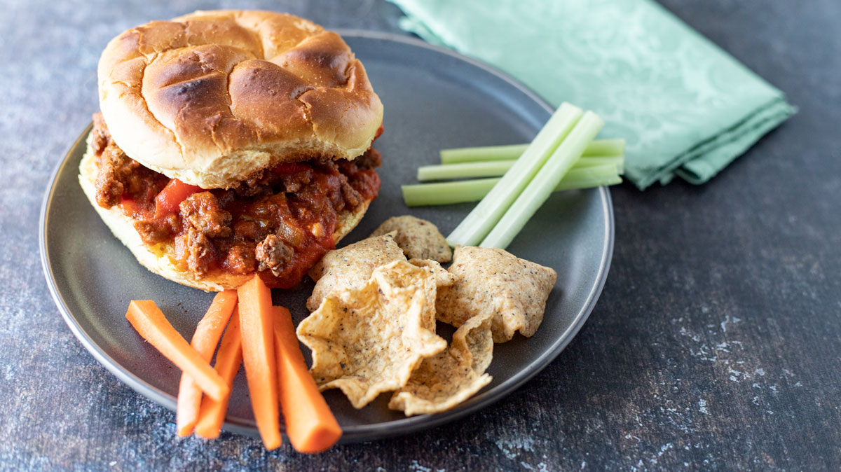 Overhead view of sandwich with chips and carrot and celery sticks.