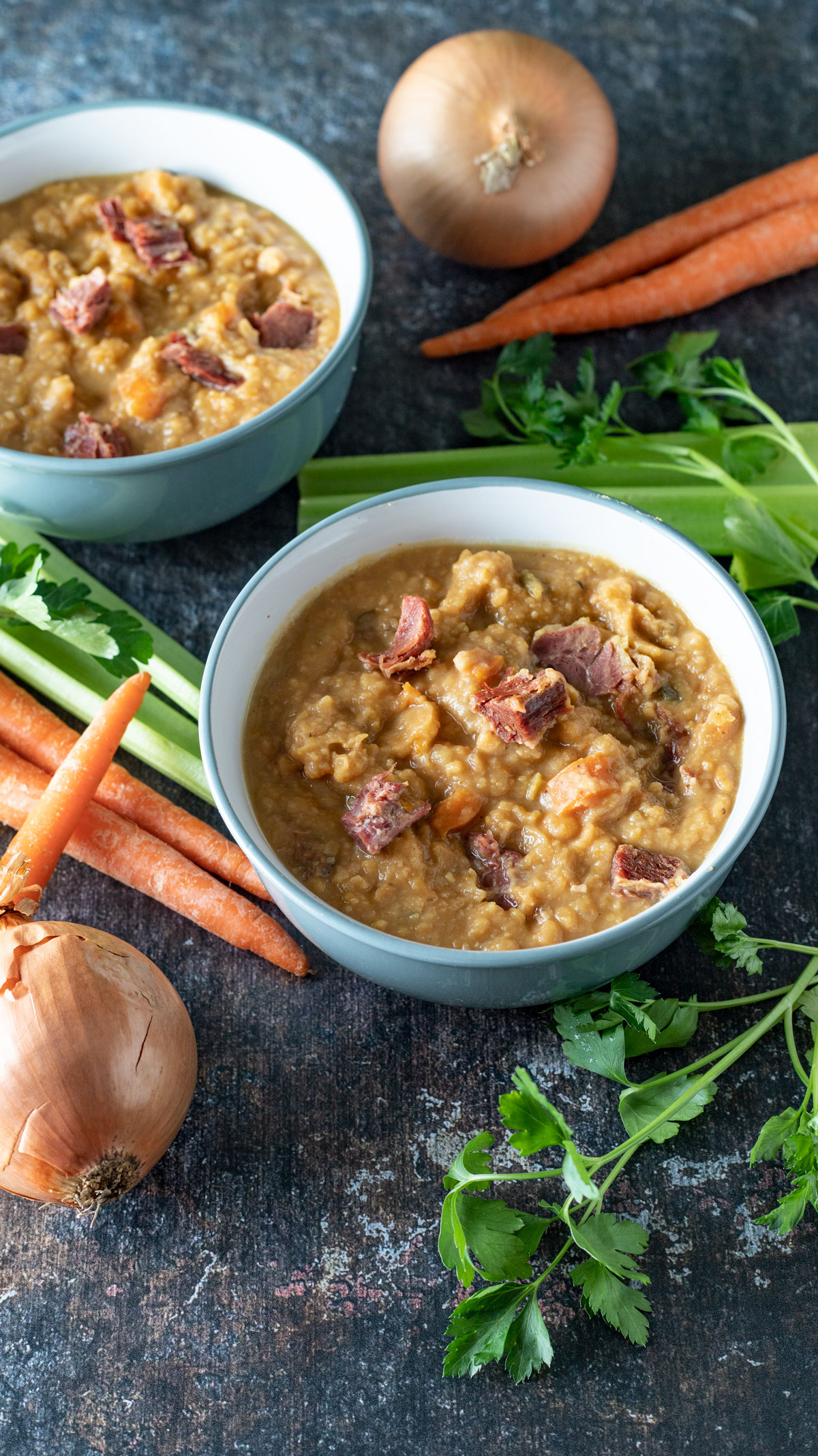 Two bowls of soup on dark background.