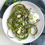 Charred garlic scapes on white plate.