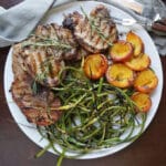 Plate of pork chops with garlic scapes and peaches.