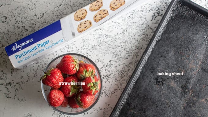 Equipment needed to freeze strawberries. Parchment, baking sheet, strawberries.