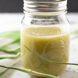 Jar of garlic scape dressing with fresh scapes.