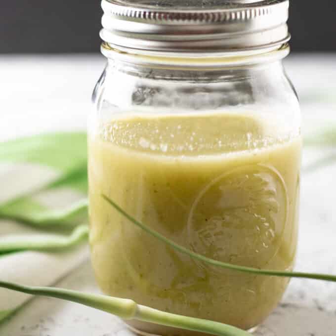 Jar of garlic scape dressing with fresh scapes.