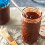 Jar of honey bbq sauce with spoon sticking out.