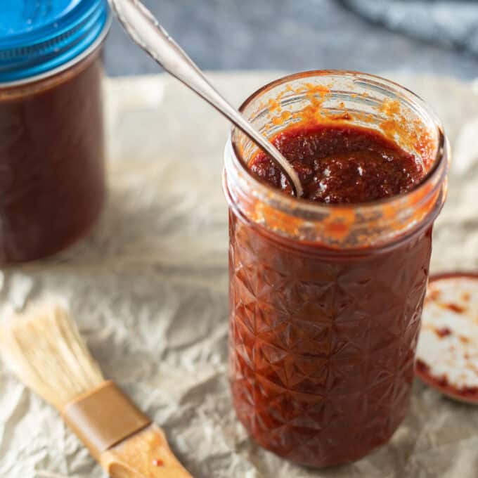 Jar of honey bbq sauce with spoon sticking out.
