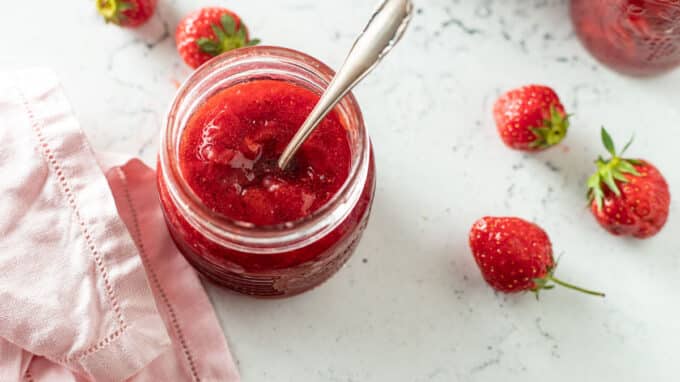 Spoon resting in jar of strawberry jam.