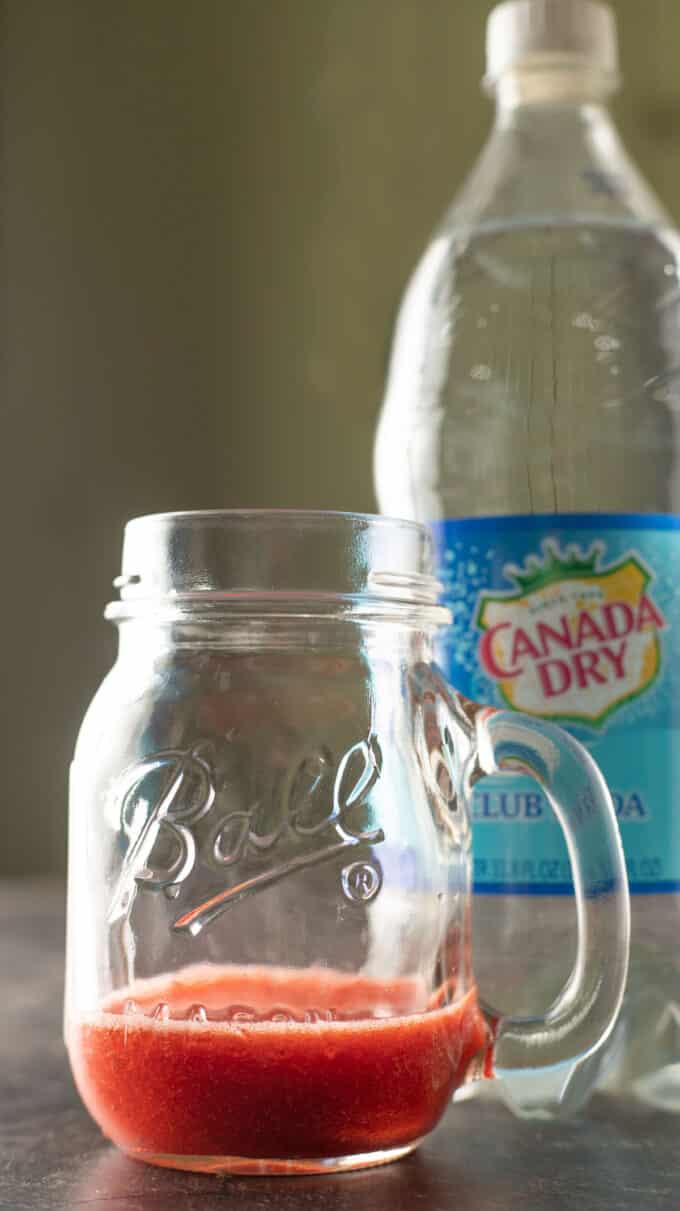 Strawberry juice in a vintage Ball jar with handle and club soda bottle.