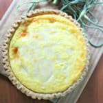 Whole quiche with garlic scapes on the side.