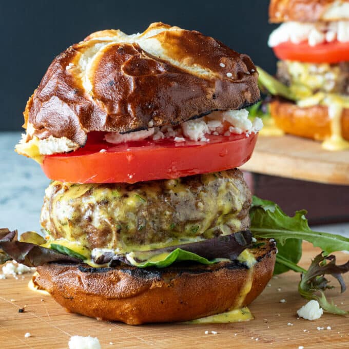 Juicy lamb burger with toppings on wooden board.