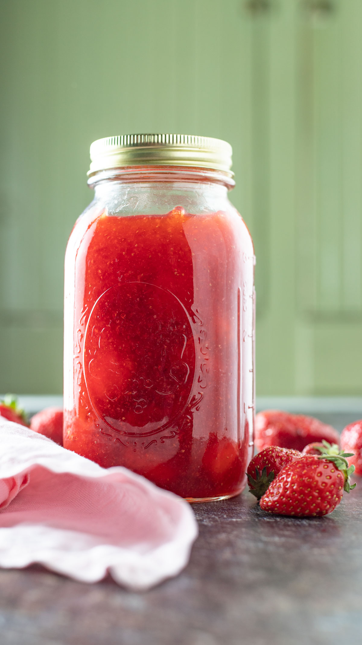 Quart jar of strawberry pie filling on black board.