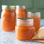 Jars of apricot jam on white board.