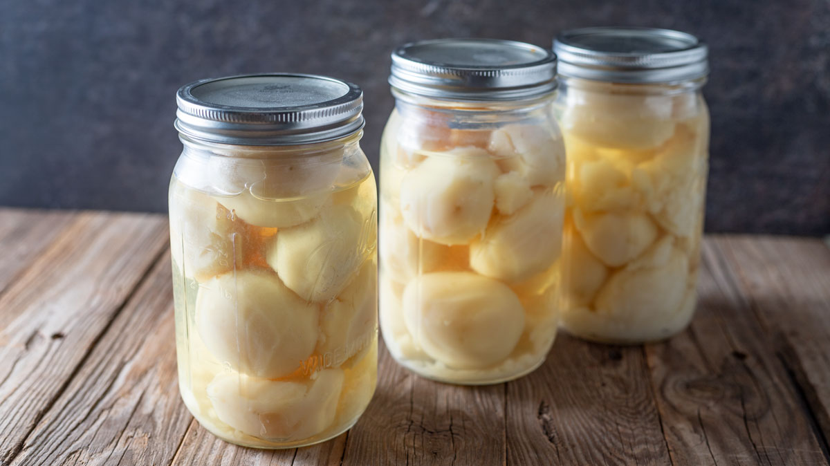 Jars of whole potatoes on barn wood board.