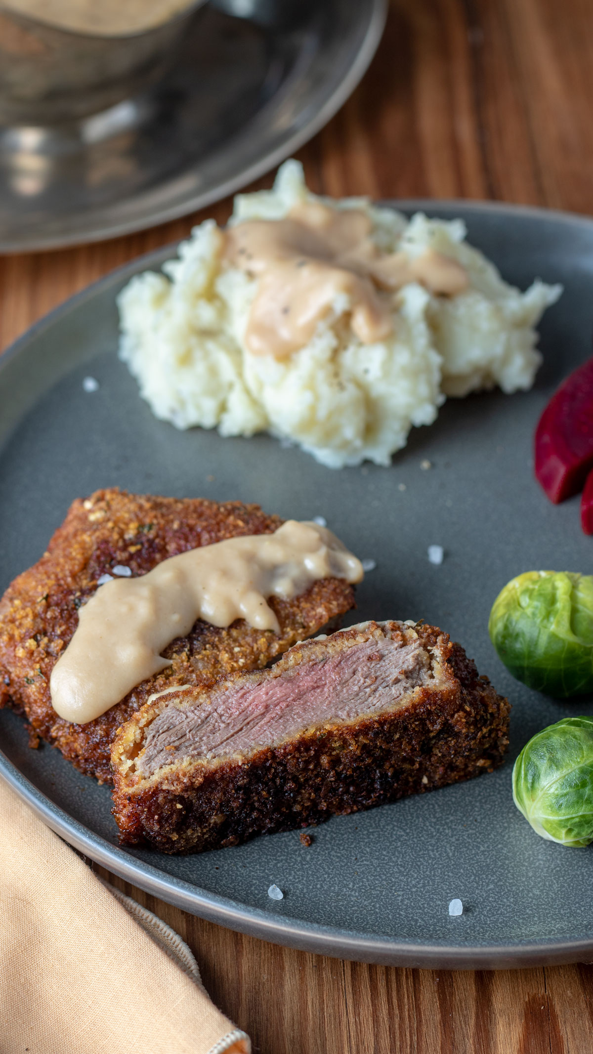 Slice chicken fried venison on gray plate.
