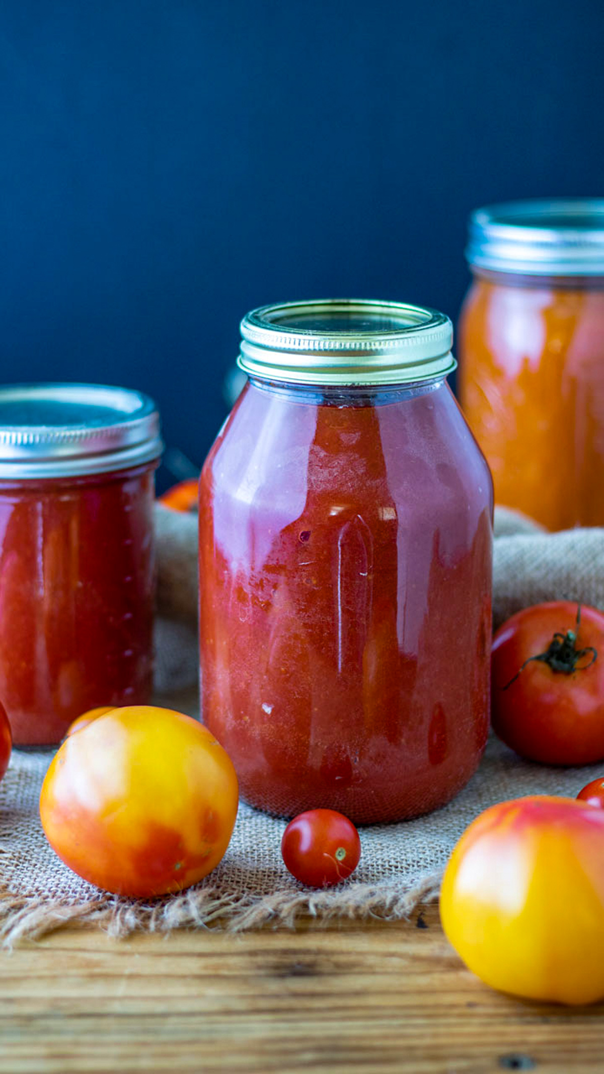 Quart jar of red tomato sauce with fresh tomatoes.