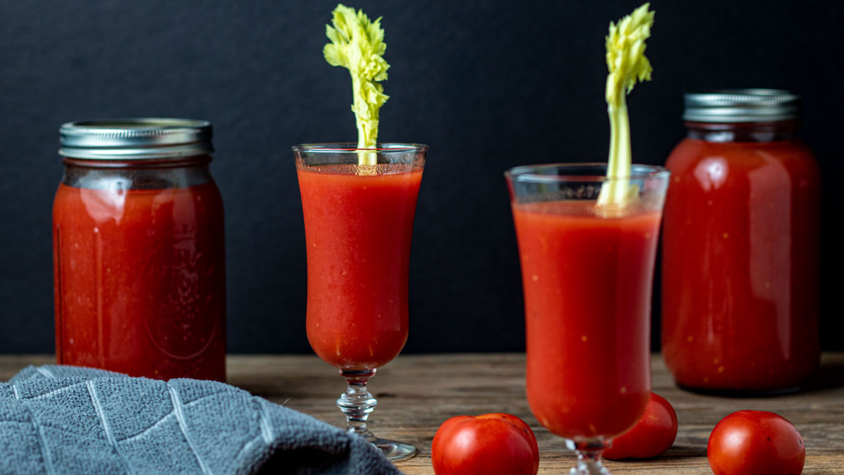 Glasses of juice on barnwood background.