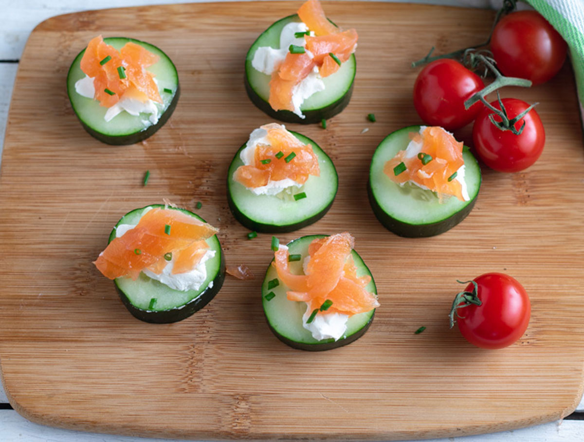 Cucumber and salmon appetizers on wooden board.