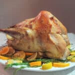 Wild turkey on platter with citrus and fresh herbs.