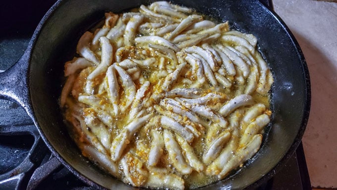 Coated smelt in cast iron pan with oil.
