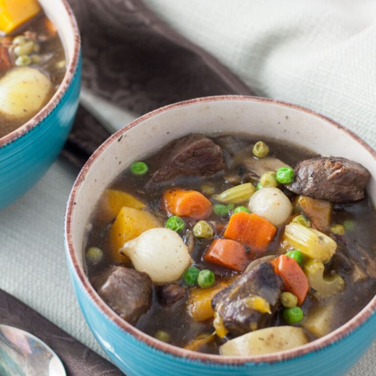 Venison stew with colorful vegetables in a bluue green bowl.