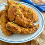 Crispy chicken tenders on white plate with blue trim.