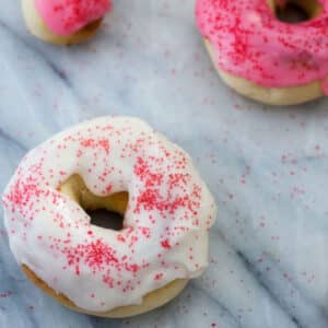 White frosted air fried doughnut with pink sprinkles.