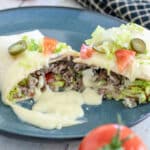 Sliced burritos smothered in cheese sauce.