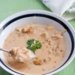 Cheesy cauliflower soup in white bowl with black trim.