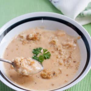 Cheesy cauliflower soup in white bowl with black trim.