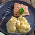 Cauliflower au gratin on gray plate with salmon filet.