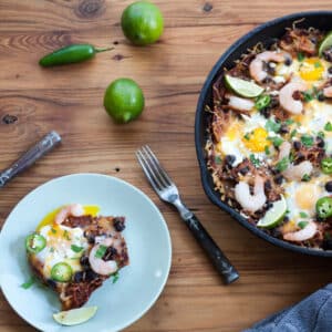 Small plate with chilaquiles next to cast iron skillet with shrimp chilaquiles.