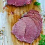 Slices of corned venison on bamboo cutting board.