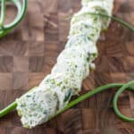 Slices of garlic scape butter with curly garlic scapes.