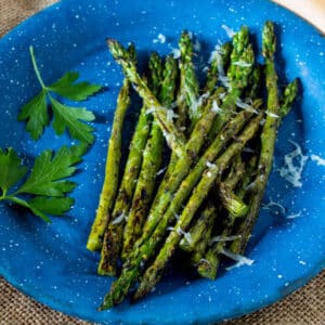 Grilled asparagus on blue pewter plate.