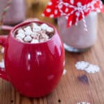 Red mug filled with hot chocolate and topped with marshmallows.