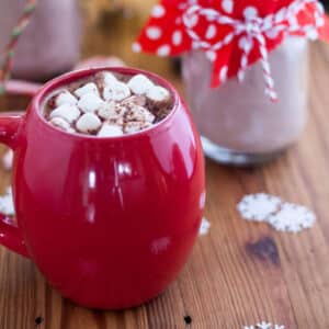 Red mug filled with hot chocolate and topped with marshmallows.