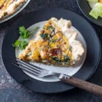 Slice of quiche on white plate with black trim.