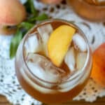 Close up in peach tea in glass with peach slices garnish.